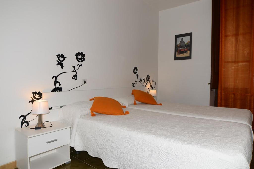 a bedroom with a white bed with orange pillows at Pensión Borrás in Girona