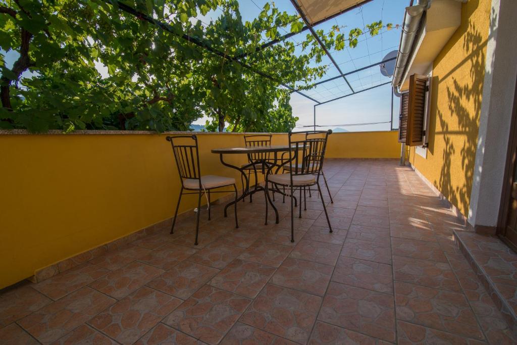 a patio with chairs and a table on a yellow wall at Rialto in Veli Lošinj