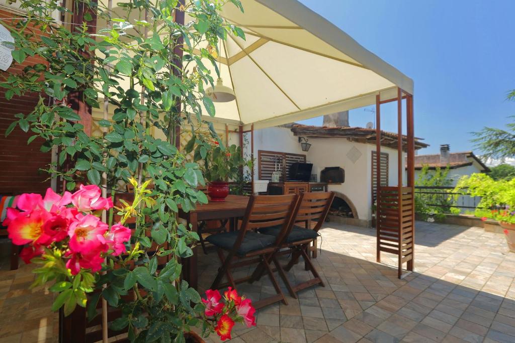 a patio with a table and chairs under an umbrella at Spaziosa villa bifamiliare in Campagnano di Roma