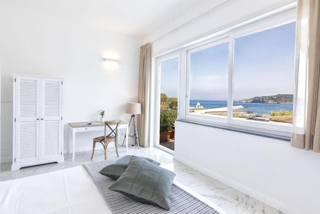 um quarto branco com uma grande janela e uma secretária em B&B Marina Garden em Ischia