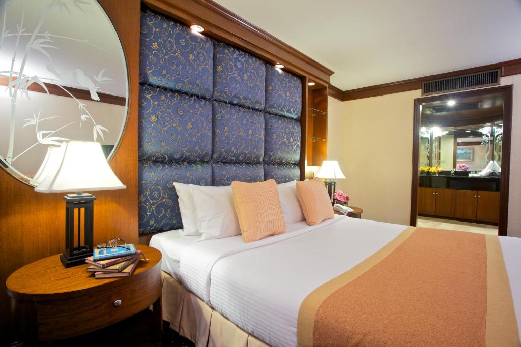 Habitación de hotel con cama grande y espejo en King Park Avenue Hotel Bangkok, en Bangkok