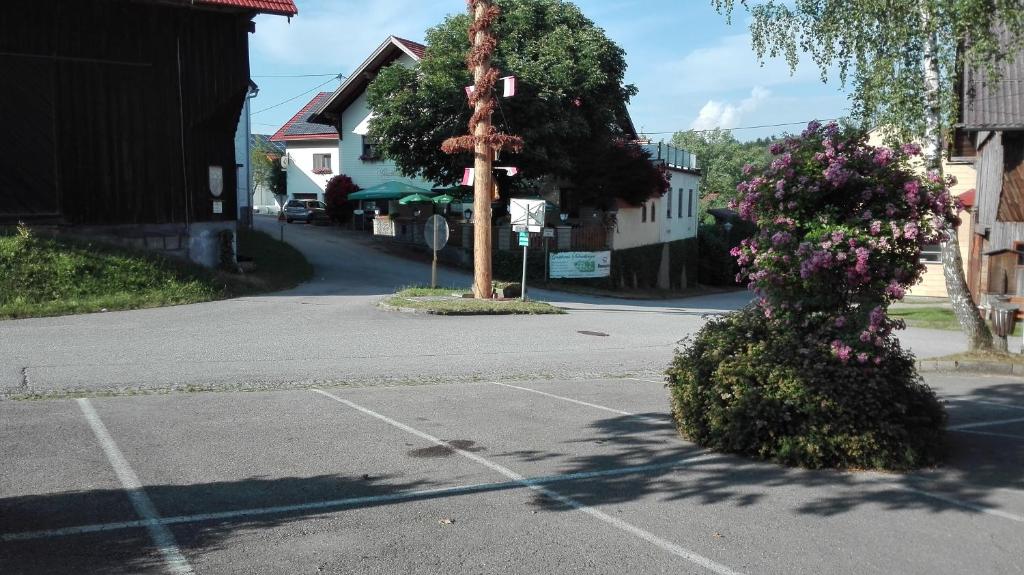 un parcheggio vuoto con albero e fiori di Gasthaus Schachinger a Tumeltsham