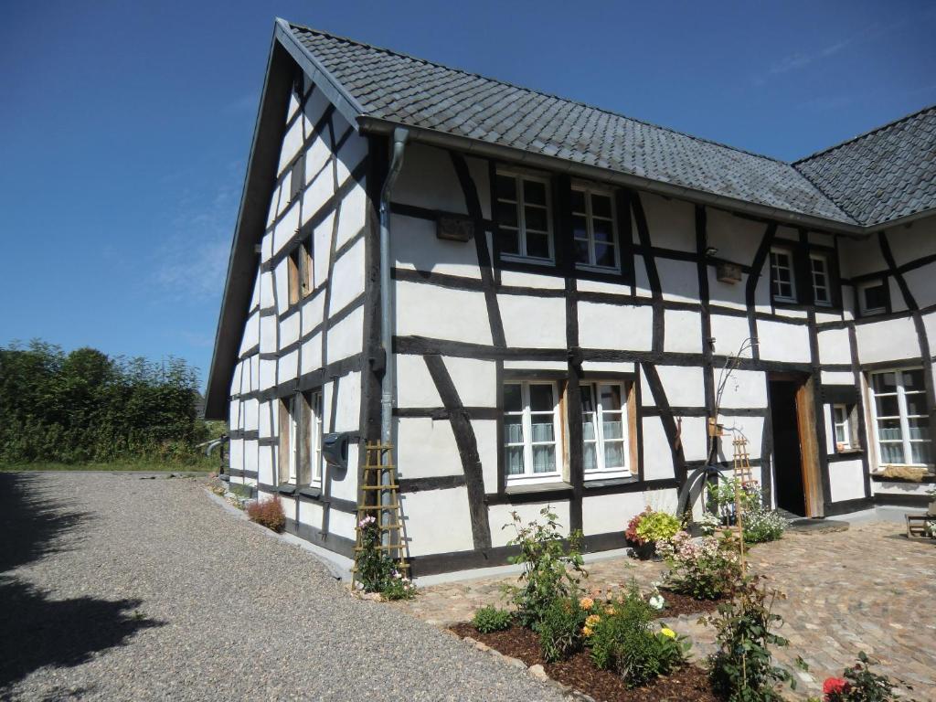 un antiguo edificio blanco y negro con porche en Ferienwohnung "im Winkelhof", en Roetgen