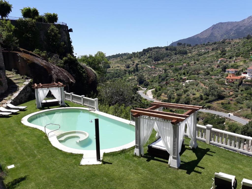 a swimming pool in the grass with a view of a mountain at Hostal El Cerro - Only Adults in Pedro Bernardo