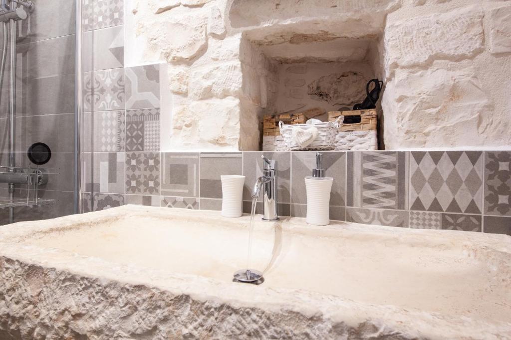 un lavabo dans une salle de bains avec un mur en pierre dans l'établissement Trullo Siamese, à Alberobello 23 autres photos