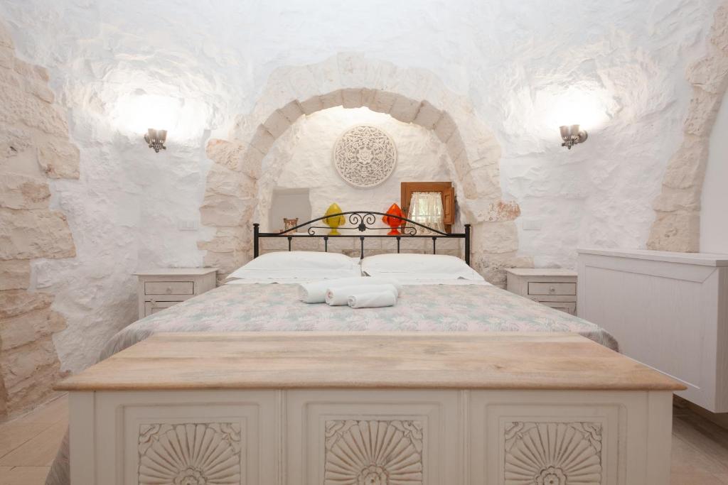 une chambre avec un grand lit dans un mur de pierre dans l'établissement Trullo Siamese, à Alberobello