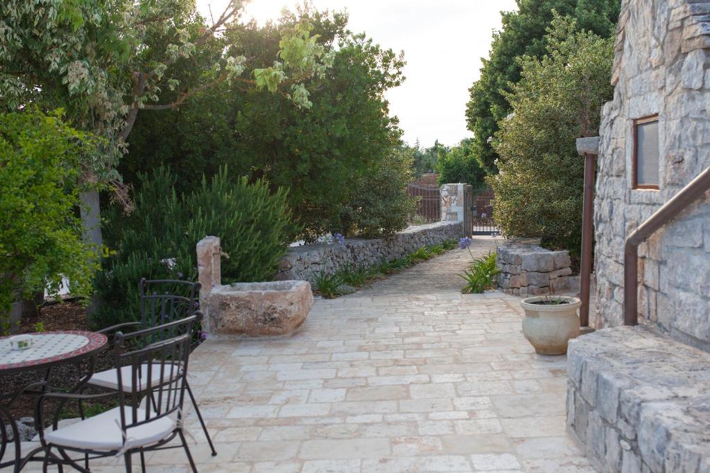 une terrasse avec des tables et des chaises et un mur en pierre dans l'établissement Trullo Siamese, à Alberobello