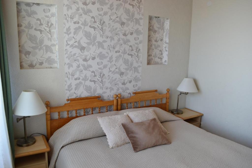 a bedroom with a bed with two lamps and a wall at Pas Virginiją in Nida