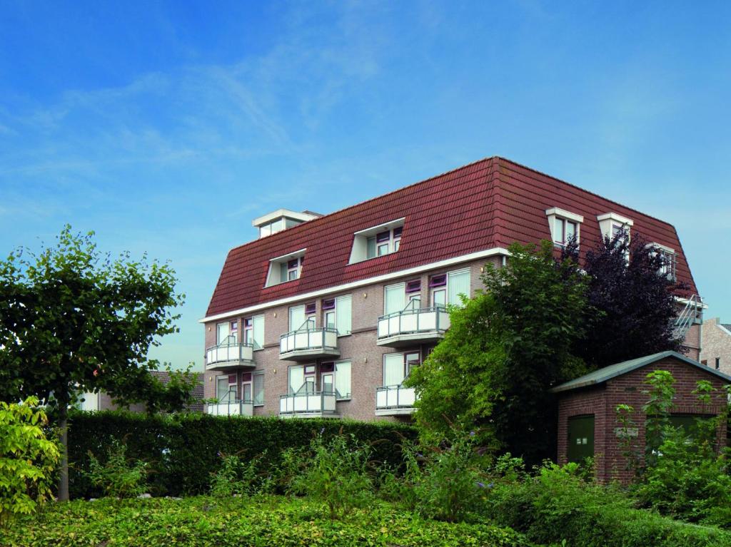 un gran edificio de ladrillo con techo rojo en Fletcher Hotel Restaurant De Gelderse Poort en Ooij