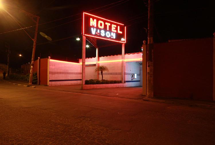 un panneau du motel sur le côté d'un bâtiment la nuit dans l'établissement Motel Vison (Próximo GRU Aeroporto), à Guarulhos