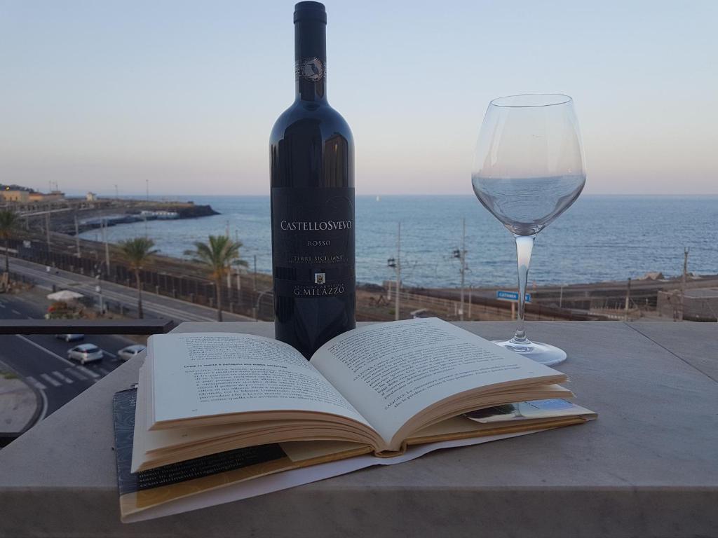an open book and a glass of wine on a table at Sea View Apartment in Catania