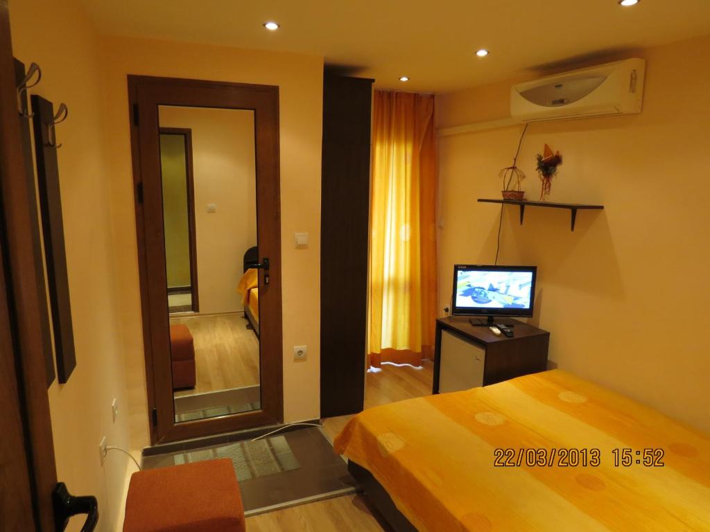 een slaapkamer met een bed, een spiegel en een televisie bij Family Hotel Lebed in Nesebar