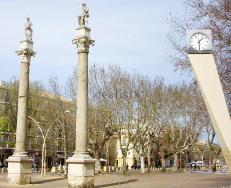un reloj en un poste frente a un edificio en APARTAMENTOS HÉRCULES SEVILLa, en Sevilla