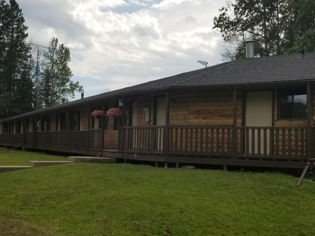 a large log cabin with a porch and grass at Schott's Lake Conference & Resort in Sundre