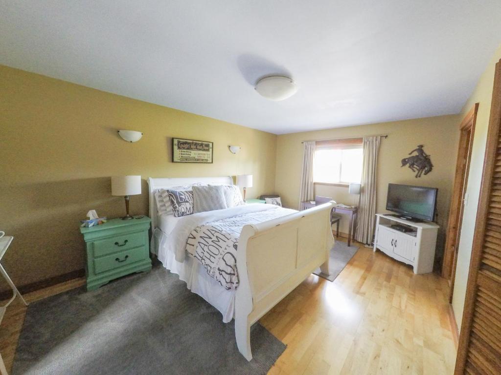 a bedroom with a white bed and a television at Money Pennies Bed and Breakfast in Campbell River