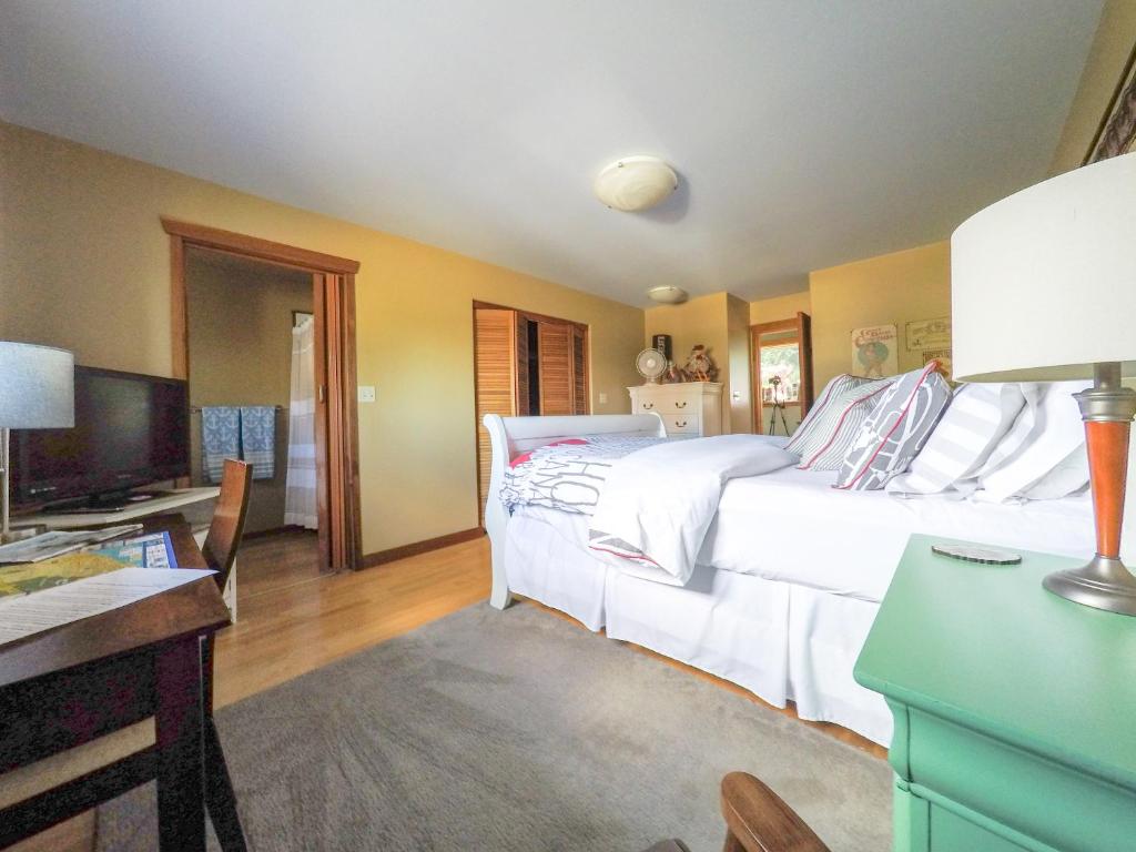 a bedroom with a large white bed and a desk at Money Pennies Bed and Breakfast in Campbell River