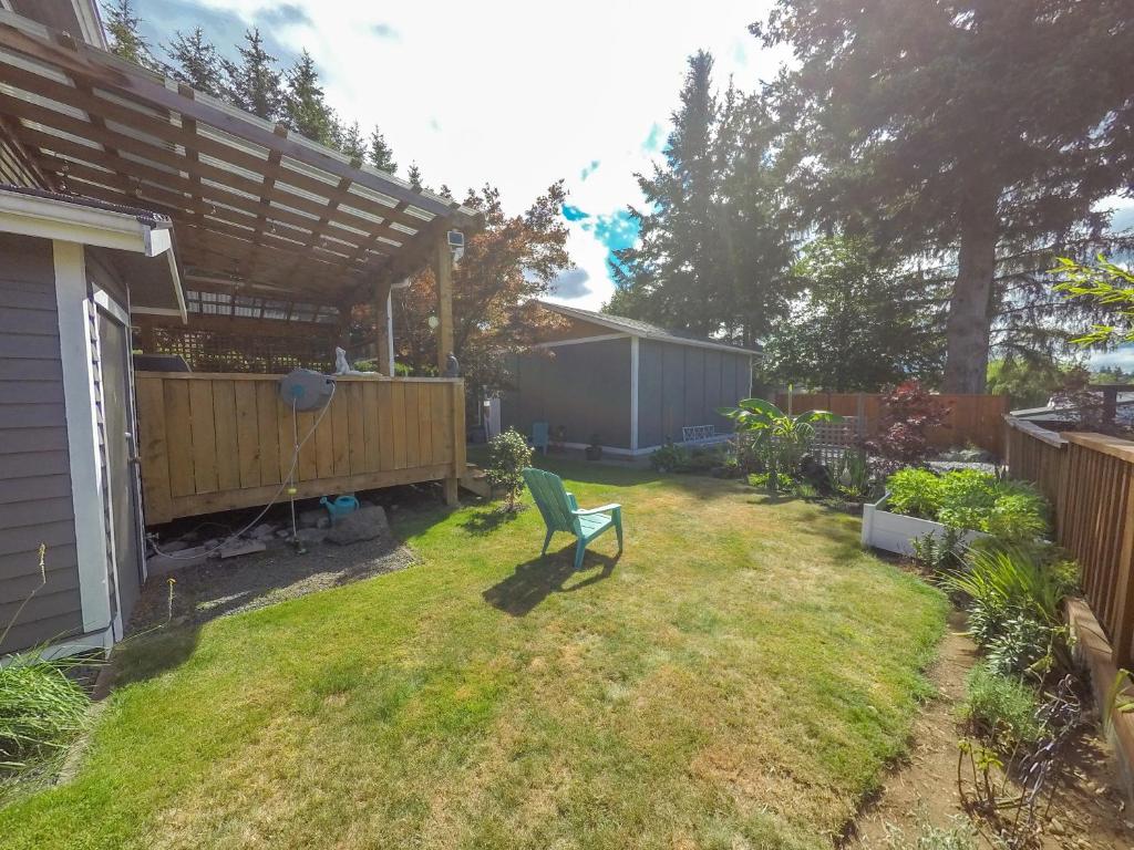 a backyard with a green chair in the yard at Money Pennies Bed and Breakfast in Campbell River