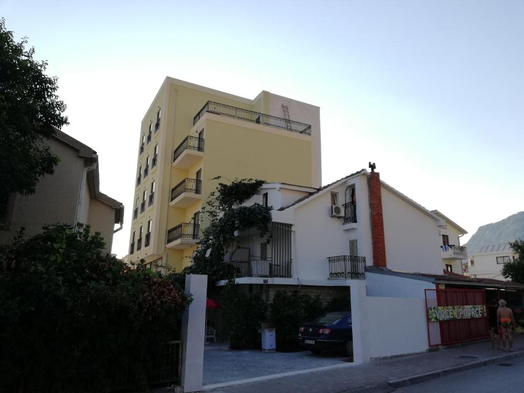 a yellow and white building with a parking lot at Apartments Marković in Budva
