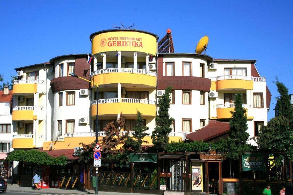 a tall yellow and white building with a sign on it at Gerdjika Hotel in Nesebar