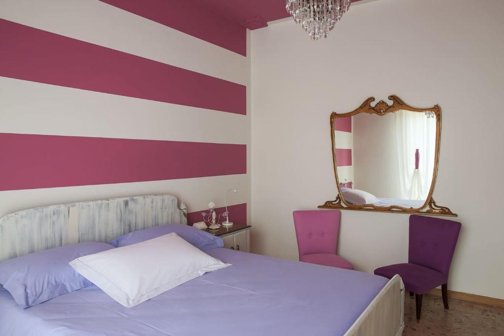 um quarto com uma cama com um espelho e cadeiras roxas em Celeste's house em Rivoltella