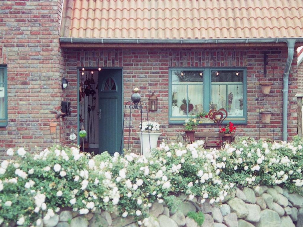 una casa de ladrillo con una puerta azul y algunas flores en Ferienhaus Wattenhus, en Büsum