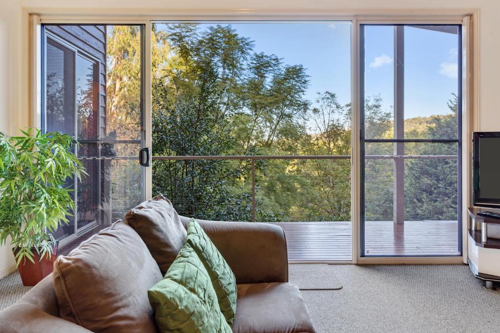uma sala de estar com um sofá e uma grande janela em Ravensbourne Escape- Kookaburra Kottage em Ravensbourne