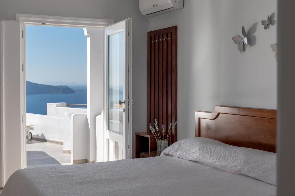 a bedroom with a bed and a view of the ocean at Villa Renos Hotel in Fira
