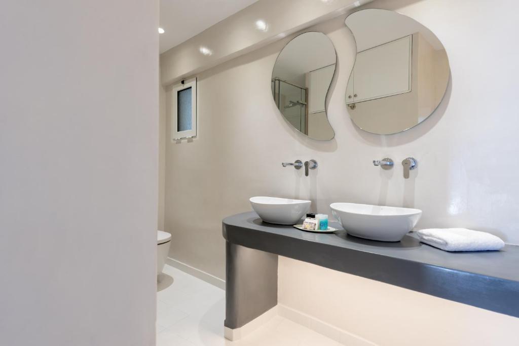 a bathroom with two sinks and a mirror at Villa Renos Hotel in Fira