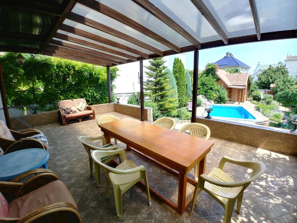 patio con mesa de madera, sillas y piscina en Котедж з басейном та сауною біля моря 2024 en Odesa