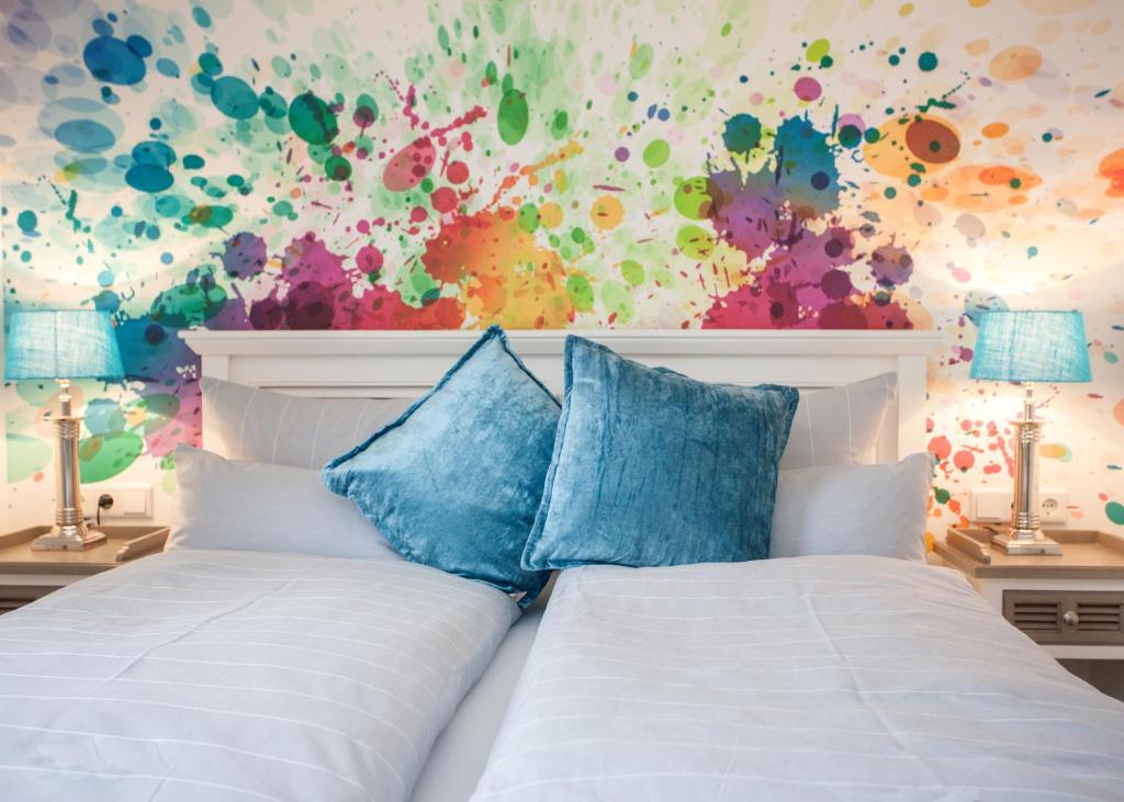 a bedroom with a white bed with a colorful wall at Die Sperre in Winterberg