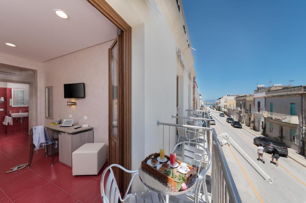 um quarto com uma varanda com um bolo sobre uma mesa em Hotel Biancolilla em San Vito lo Capo