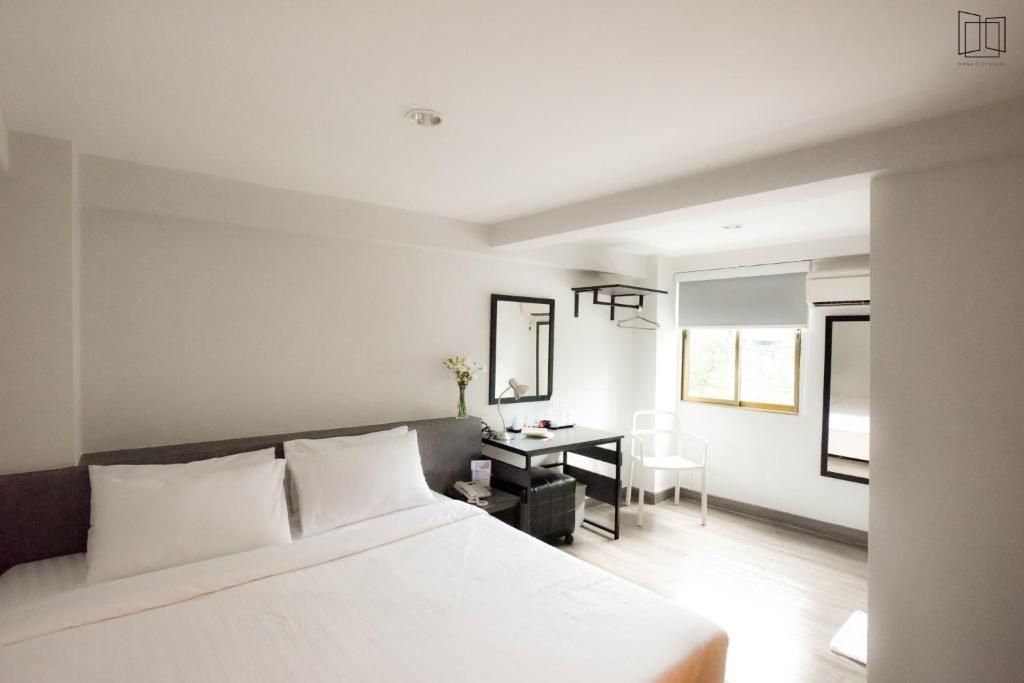 a bedroom with a white bed and a desk at Nana City Hotel in Bangkok