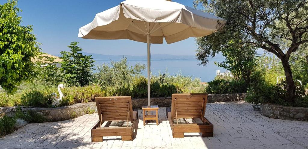 two chairs and an umbrella on a brick patio at Verga Apartments & Suites in Kalamata