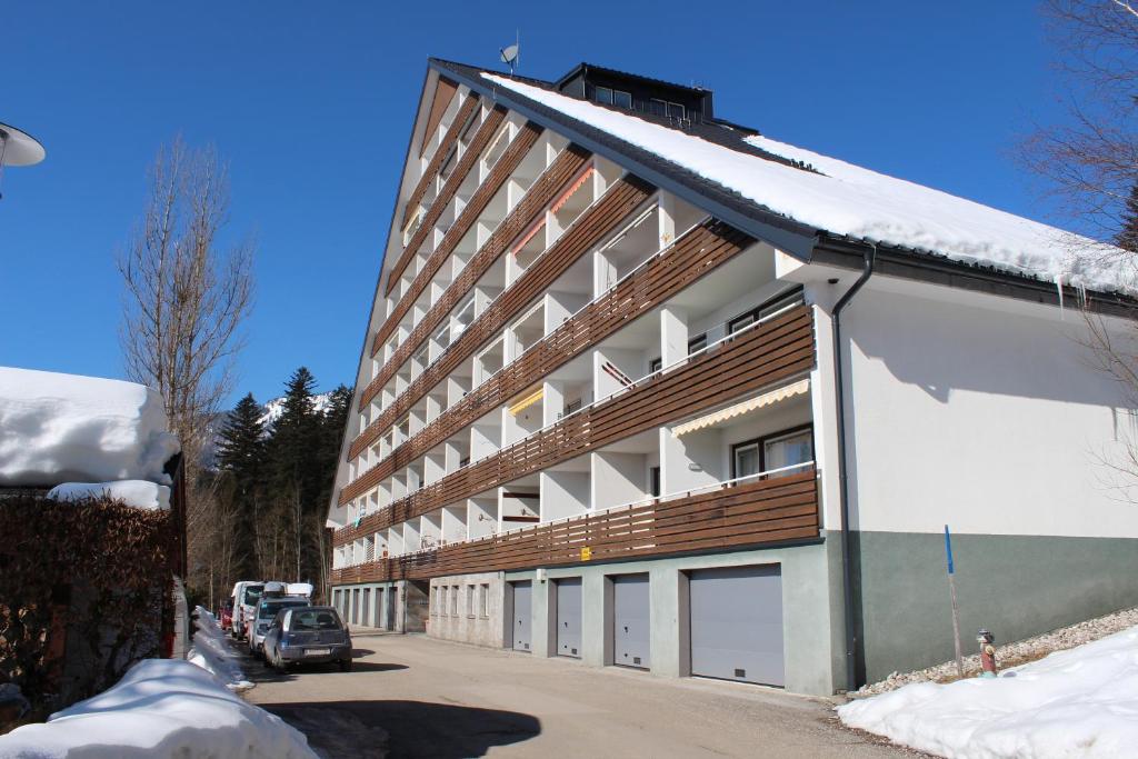 un grand bâtiment avec quatre portes de garage et de la neige dans l'établissement Familienapartment Sunnseitn, à Bad Mitterndorf
