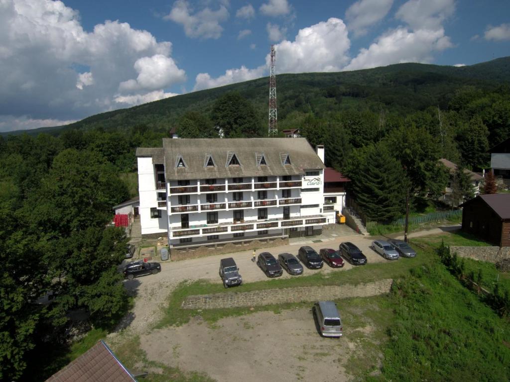 a large white building with cars parked in a parking lot at Cabana Claris in Văliug