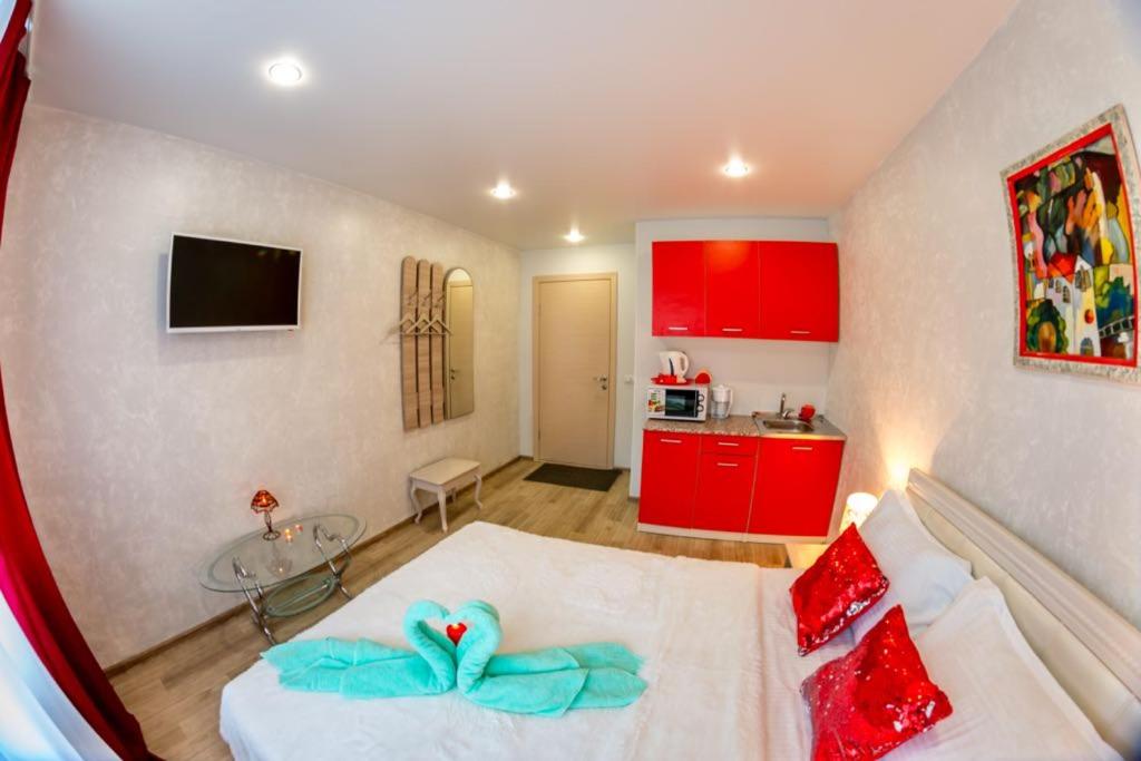 ブラゴヴェシチェンスクにあるSweet Homeのベッド付きの部屋、赤いキャビネット付きのキッチン