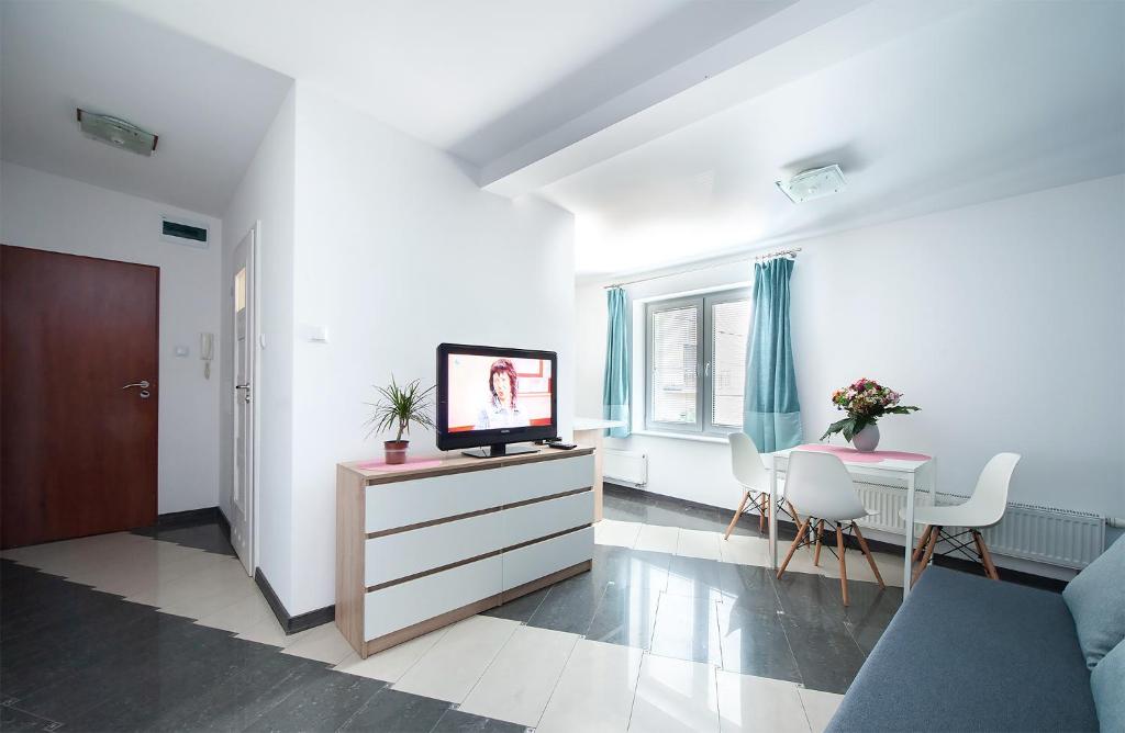 uma sala de estar com uma televisão e uma mesa com cadeiras em PORT-ŁÓDŹ Apartment by PinPoint em Lódź