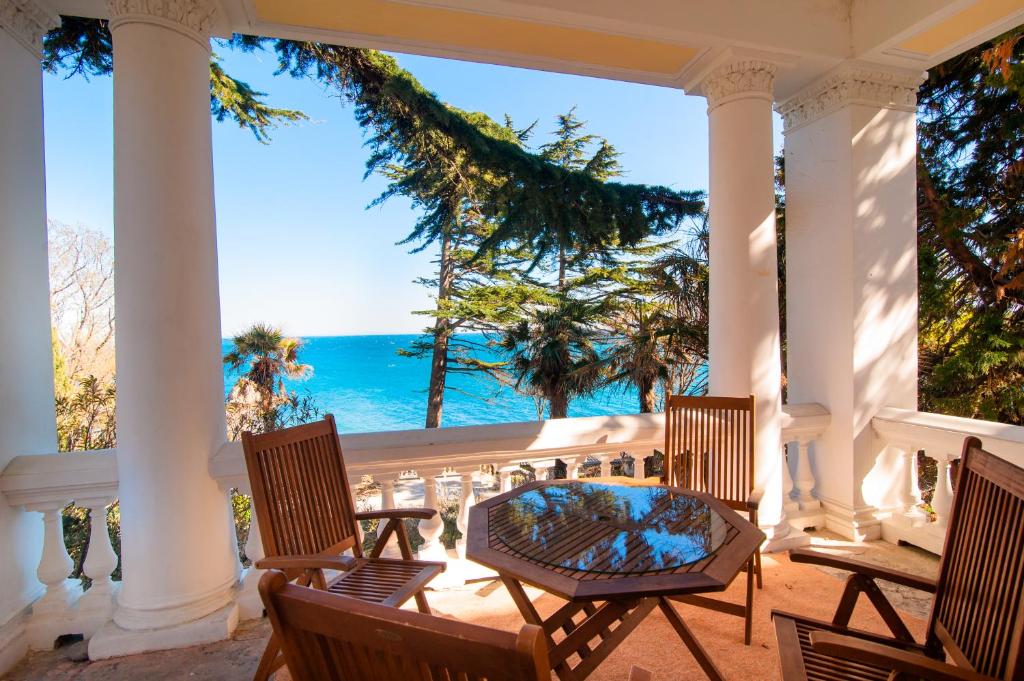 een veranda met stoelen en een tafel en de oceaan bij Ligo Morskaya in Simeiz