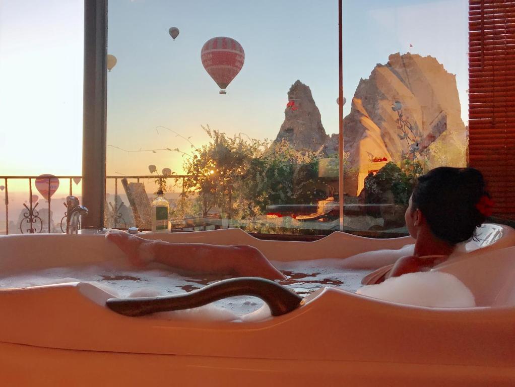 a woman laying in a hot tub with a snake at Hermes Cave Hotel in Uchisar