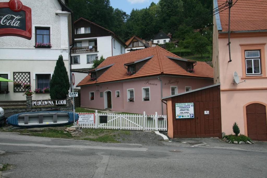 ein rosafarbenes Haus mit einem weißen Zaun neben einem Gebäude in der Unterkunft Penzion U Haničky in Rožmberk nad Vltavou