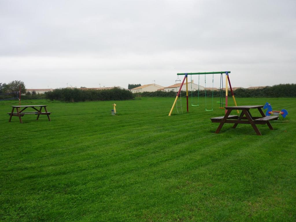 two picnic tables and a swing set in a field at Chambres d&#39;Hôtes Mazurier in Cozes
