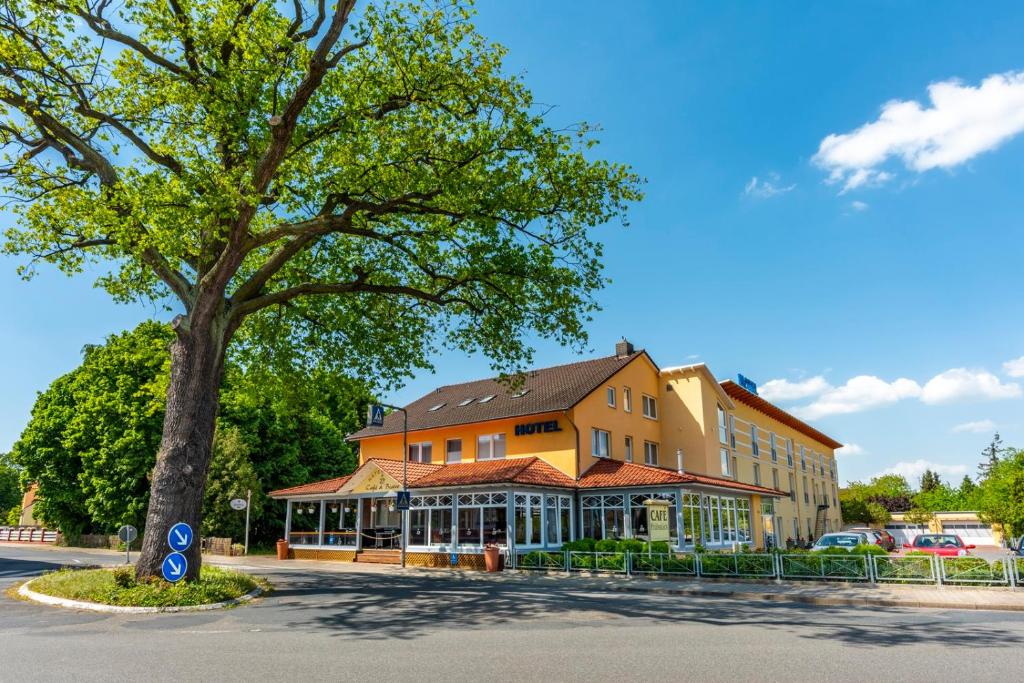 een groot gebouw met een boom ervoor bij Komfort-Hotel Katerberg in Lüchow