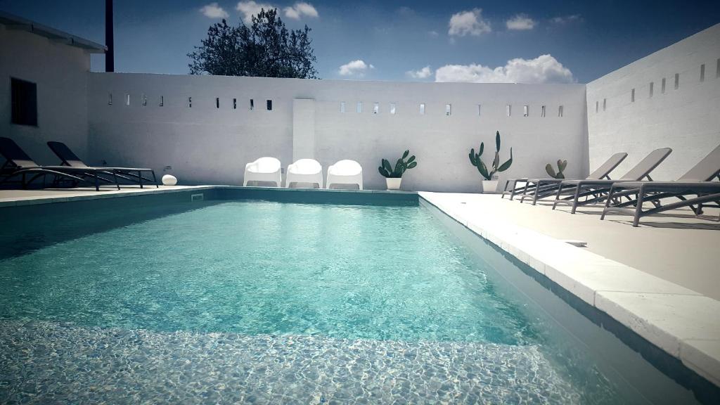 ein Pool in einem Haus mit Stühlen um ihn herum in der Unterkunft Mazzara Farm in Manduria