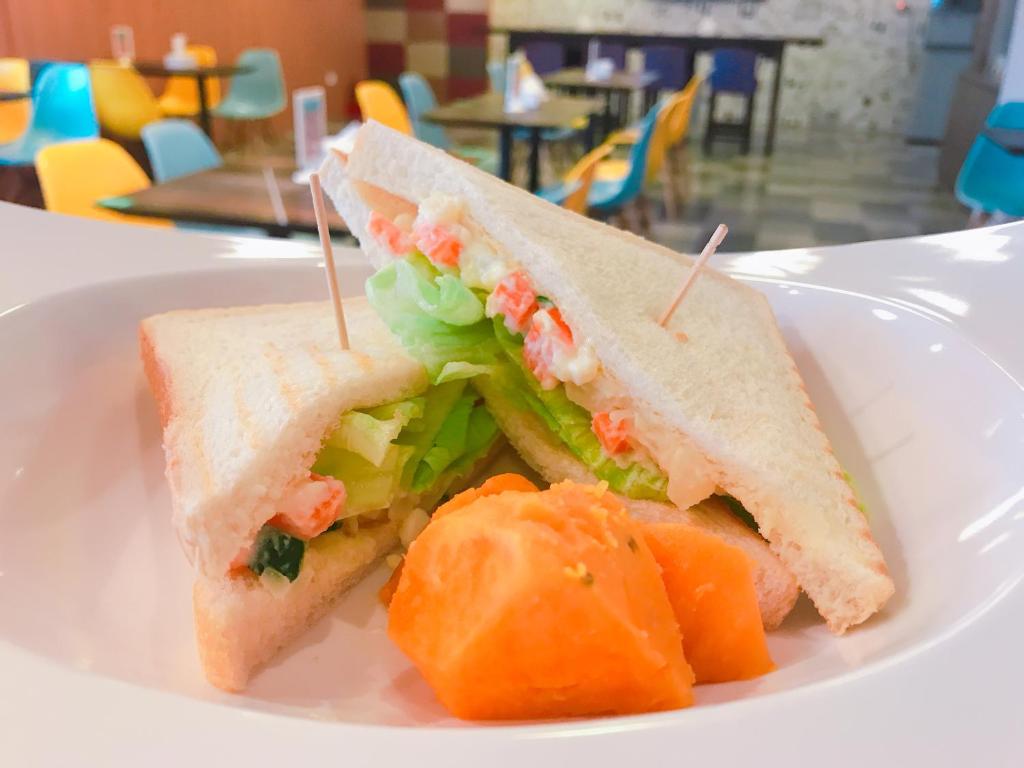 a sandwich and some fruit on a white plate at Single Inn - Taipei in Taipei