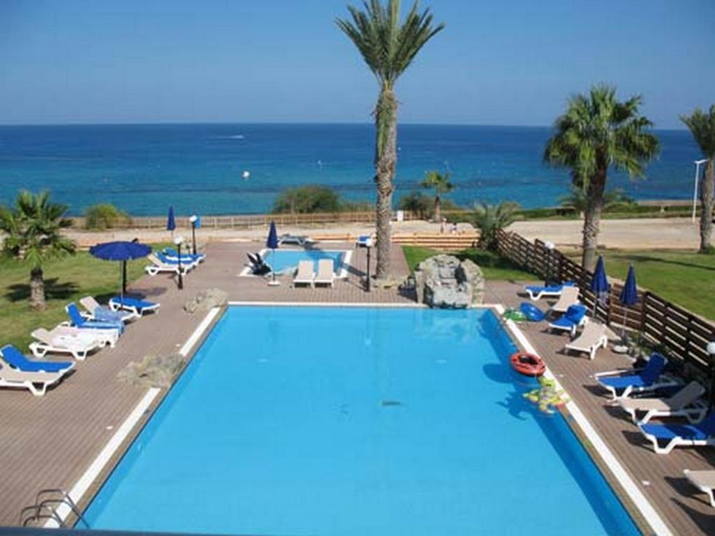 a swimming pool with chairs and the ocean in the background at one bedroom apartment in Fig tree bay in Protaras