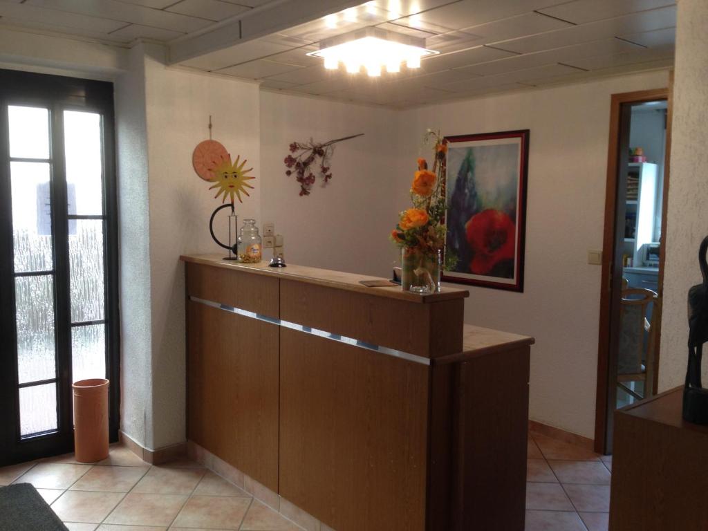a waiting room with a reception desk and flowers at Pension Anna in Löbau