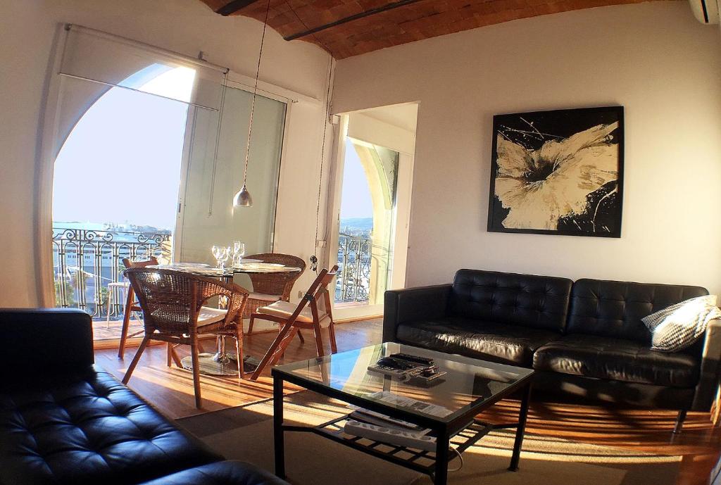 ein Wohnzimmer mit einem schwarzen Ledersofa und einem Tisch in der Unterkunft Barceloneta Port Ramblas in Barcelona