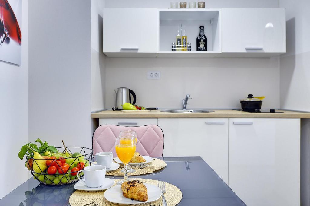 a kitchen with a table with food and a bowl of fruit at D&A Amphitheatre Apartments with free parking in Pula