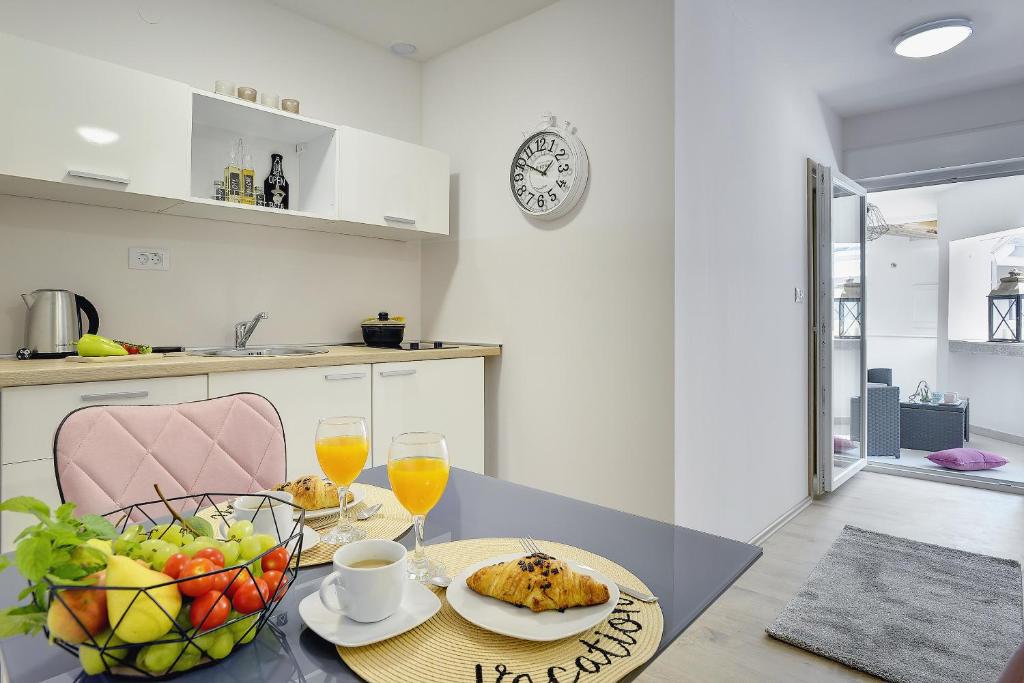 a table with two plates of food and a bowl of fruit at D&A Amphitheatre Apartments with free parking in Pula