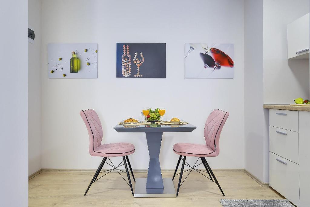a table with two pink chairs and a table with food on it at D&A Amphitheatre Apartments with free parking in Pula